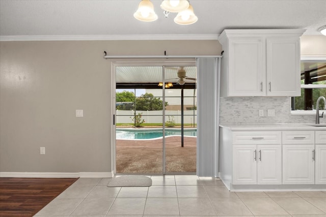 2725 White Magnolia Loop, Clermont, FL 34711 - kitchen with a chandelier, healthy amount of natural light, white cabinets, light countertops, and ornamental molding