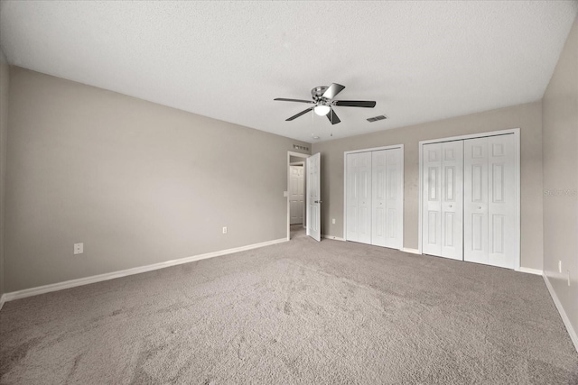 2725 White Magnolia Loop, Clermont, FL 34711 - unfurnished bedroom with two closets, carpet floors, a ceiling fan, and a textured ceiling