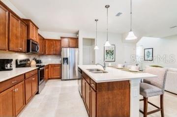 1512 Mumbai Way, Kissimmee, FL 34747 - kitchen featuring stainless steel appliances, pendant lighting, a kitchen breakfast bar, light countertops, and a kitchen island with sink