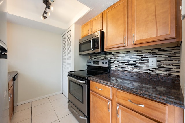 1300 Arlington Ln NE Unit 111, Palm Bay, FL 32905 - kitchen with stainless steel appliances, tasteful backsplash, light tile patterned flooring, dark stone countertops, and brown cabinetry