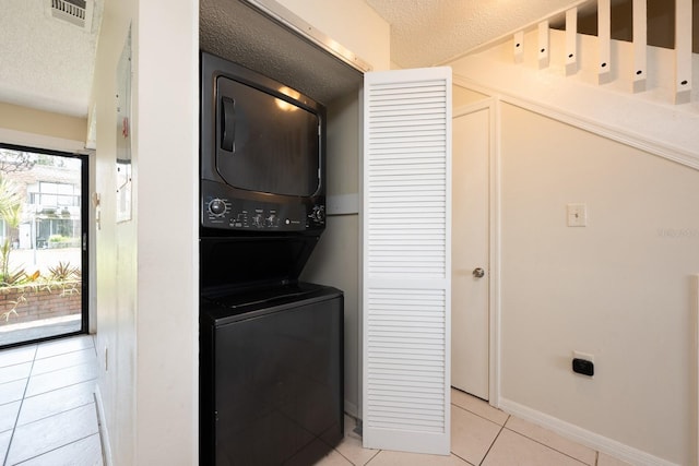 1300 Arlington Ln NE Unit 111, Palm Bay, FL 32905 - washroom with estacked washer and dryer, light tile patterned flooring, and a textured ceiling