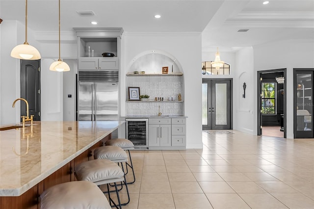 2873 Bellwind Cir, Rockledge, FL 32955 - kitchen featuring wine cooler, stainless steel built in refrigerator, light tile patterned floors, backsplash, and a breakfast bar area