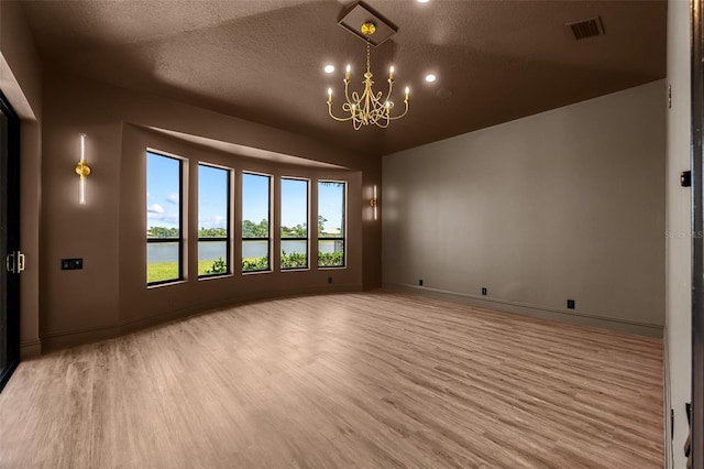 2873 Bellwind Cir, Rockledge, FL 32955 - empty room with light wood-style floors, a chandelier, a textured ceiling, recessed lighting, and a water view