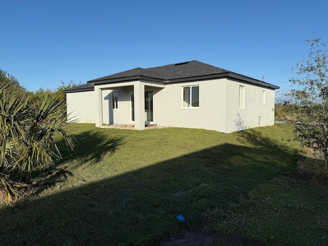 10071 Kingsville Dr, Port Charlotte, FL 33981 - back of property with a lawn, stucco siding, and roof with shingles