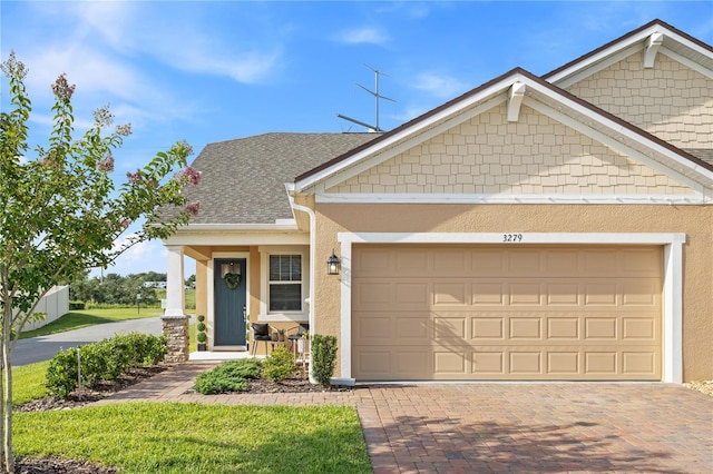 3279 Canna Lily Pl, Clermont, FL 34711 - craftsman-style home featuring an attached garage, stucco siding, decorative driveway, and a shingled roof