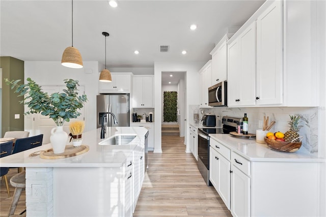 3279 Canna Lily Pl, Clermont, FL 34711 - kitchen featuring stainless steel appliances, a kitchen bar, white cabinets, light wood finished floors, and decorative backsplash