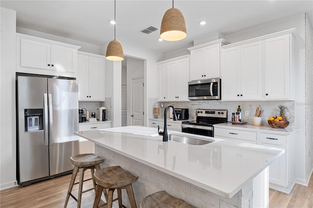 3279 Canna Lily Pl, Clermont, FL 34711 - kitchen with stainless steel appliances, tasteful backsplash, light wood-type flooring, white cabinetry, and recessed lighting