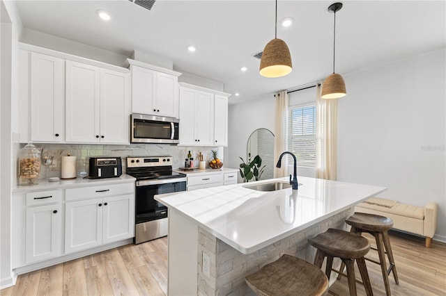 3279 Canna Lily Pl, Clermont, FL 34711 - kitchen with appliances with stainless steel finishes, decorative backsplash, light wood finished floors, light countertops, and a kitchen bar