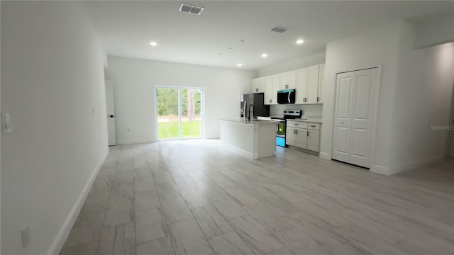 3551 W Fleece Dr, Dunnellon, FL 34433 - kitchen with stainless steel appliances, open floor plan, white cabinets, light countertops, and an island with sink