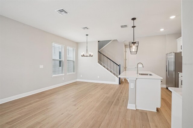 16526 Silver Brook Way, Winter Garden, FL 34787 - kitchen with stainless steel fridge, light wood-style floors, a chandelier, light countertops, and white cabinets