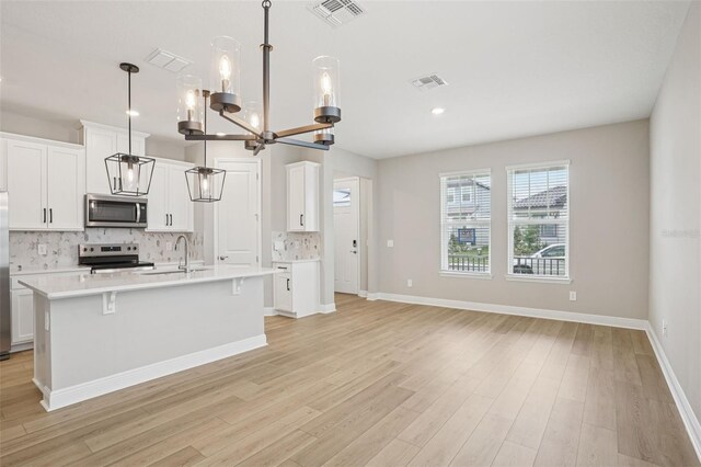 16526 Silver Brook Way, Winter Garden, FL 34787 - kitchen featuring appliances with stainless steel finishes, backsplash, light countertops, an island with sink, and a chandelier