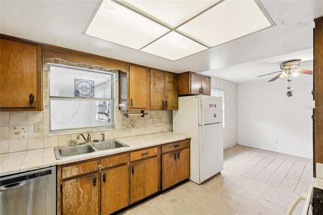 2020 Cocos Ct, Winter Park, FL 32792 - kitchen featuring dishwasher, freestanding refrigerator, tile countertops, brown cabinets, and wallpapered walls