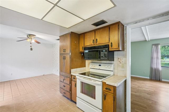 2020 Cocos Ct, Winter Park, FL 32792 - kitchen with white range with electric cooktop, black microwave, brown cabinets, tile counters, and beamed ceiling