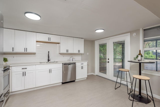 709 1st Ave NE, Largo, FL 33770 - kitchen featuring appliances with stainless steel finishes, french doors, light countertops, light wood-style flooring, and white cabinetry