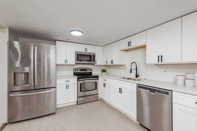 709 1st Ave NE, Largo, FL 33770 - kitchen with appliances with stainless steel finishes, light countertops, white cabinetry, and light wood-style flooring
