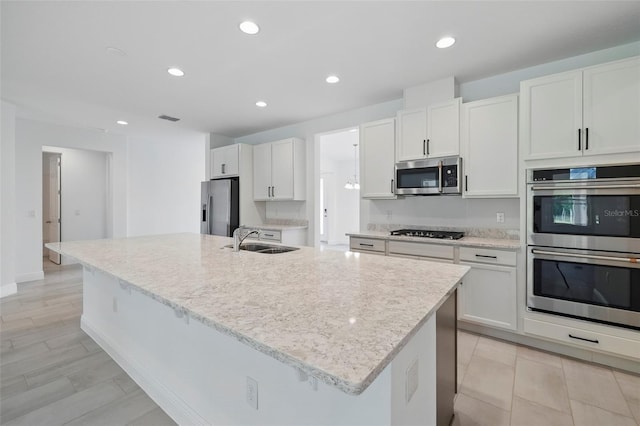 5204 Obsidian Gate Dr, Mount Dora, FL 32757 - kitchen featuring appliances with stainless steel finishes, a large island with sink, white cabinets, recessed lighting, and light stone counters
