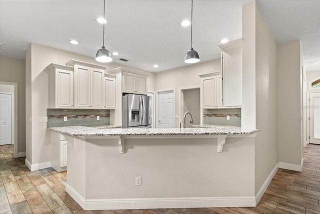 917 Southern Oak Ln, Apopka, FL 32712 - kitchen with stainless steel refrigerator with ice dispenser, a peninsula, backsplash, light stone countertops, and a breakfast bar area