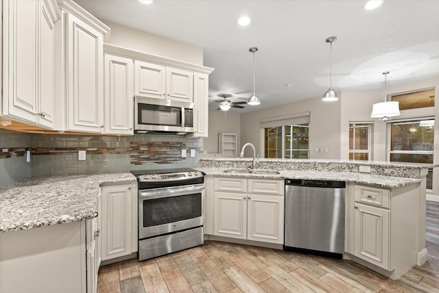 917 Southern Oak Ln, Apopka, FL 32712 - kitchen with appliances with stainless steel finishes, a peninsula, tasteful backsplash, light wood finished floors, and recessed lighting