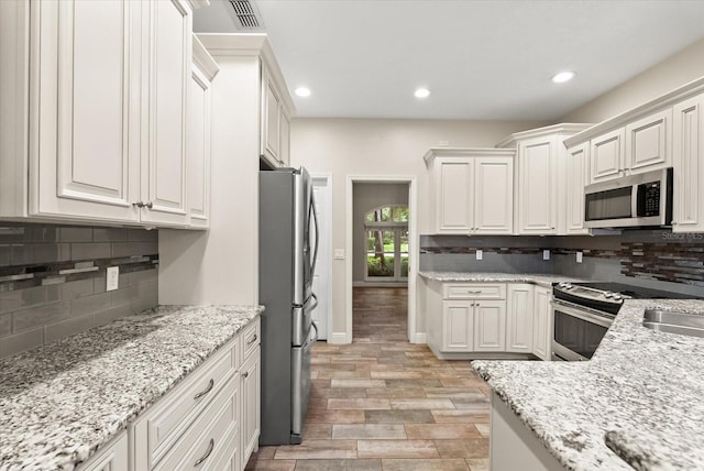917 Southern Oak Ln, Apopka, FL 32712 - kitchen with stainless steel appliances, tasteful backsplash, recessed lighting, light stone countertops, and white cabinets