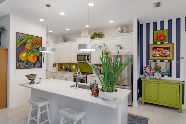 2440 Pawtucket Pass, Mount Dora, FL 32757 - kitchen with stainless steel appliances, white cabinetry, a breakfast bar area, an island with sink, and light tile patterned floors