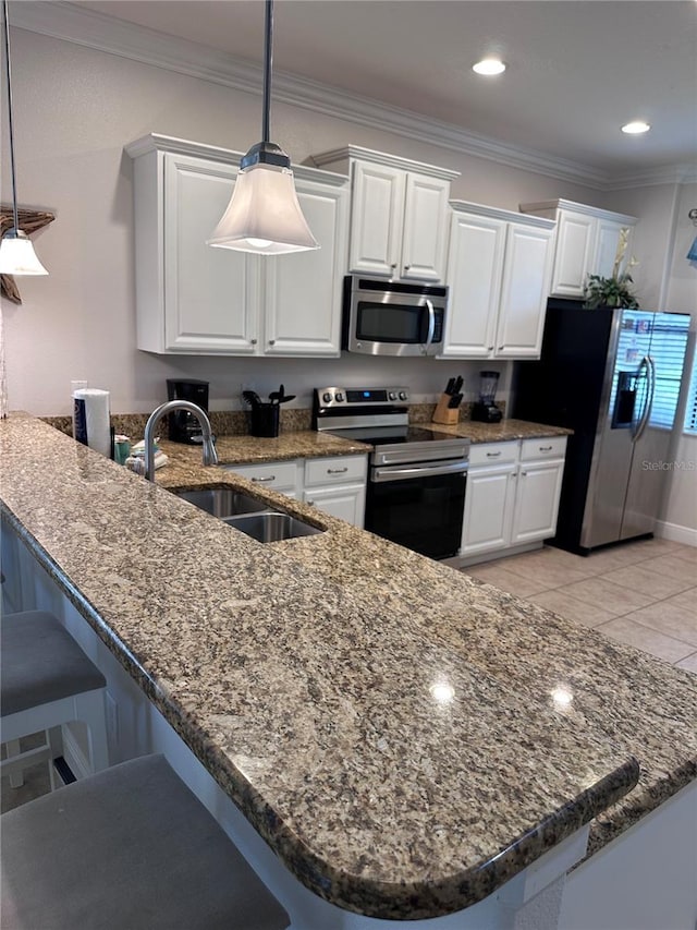 1452 Moon Valley Dr, Davenport, FL 33896 - kitchen with stainless steel appliances, a kitchen bar, white cabinets, ornamental molding, and recessed lighting