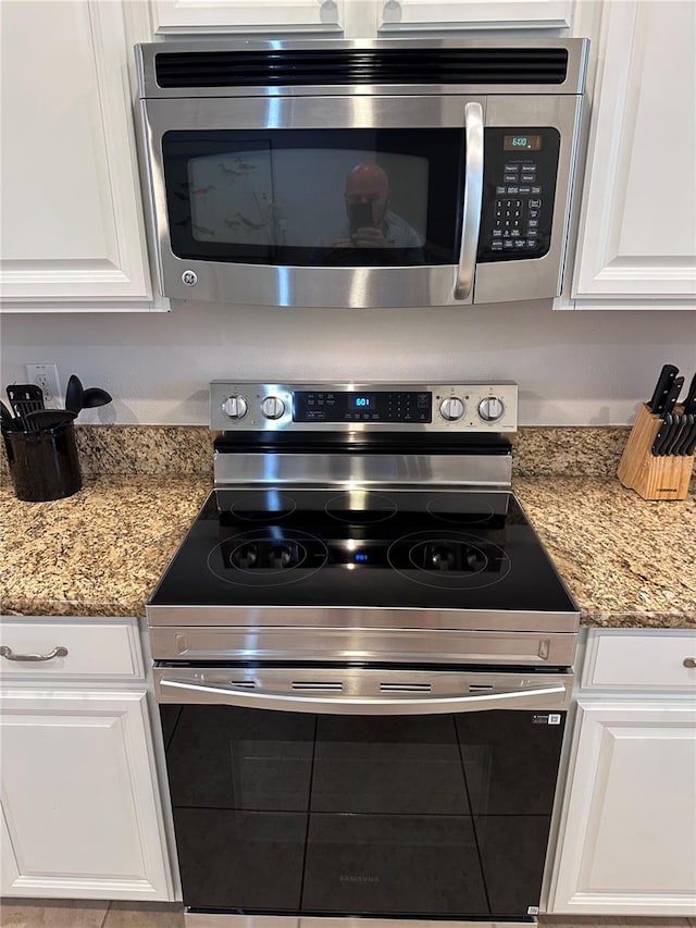 1452 Moon Valley Dr, Davenport, FL 33896 - kitchen view of appliances with stainless steel finishes, white cabinets, and light stone counters