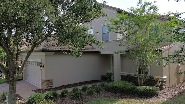 1452 Moon Valley Dr, Davenport, FL 33896 - view of front of house featuring stone siding, stucco siding, a garage, a tiled roof, and decorative driveway