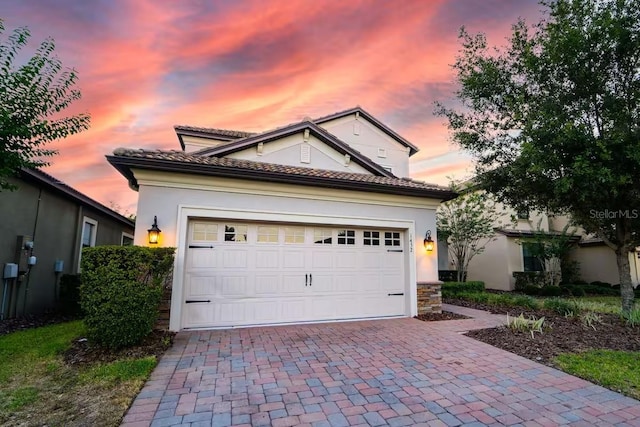1452 Moon Valley Dr, Davenport, FL 33896 - view of front of property with decorative driveway, an attached garage, a tile roof, stone siding, and stucco siding