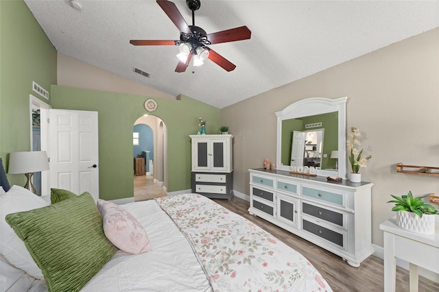 2042 Hayfield Way, Apopka, FL 32712 - bedroom with arched walkways, vaulted ceiling, wood finished floors, a textured ceiling, and a ceiling fan
