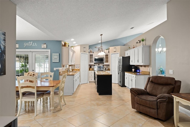 2042 Hayfield Way, Apopka, FL 32712 - kitchen featuring appliances with stainless steel finishes, open floor plan, an island with sink, a textured ceiling, and glass insert cabinets