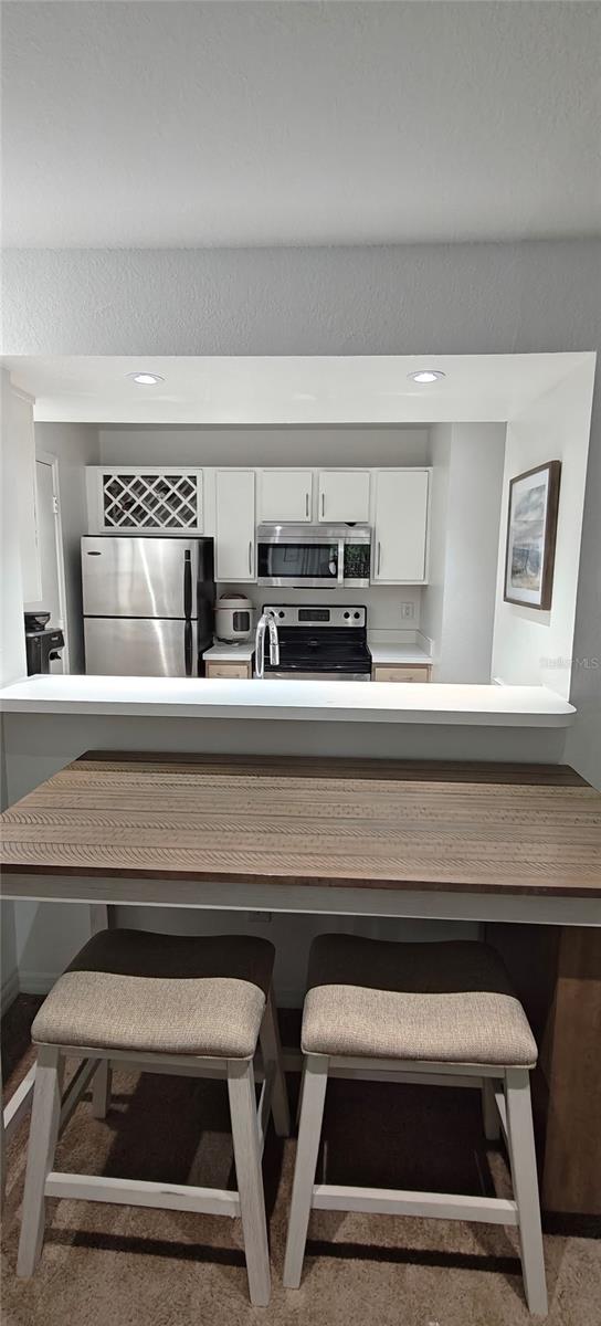 7220 Westpointe Blvd Unit 1429, Orlando, FL 32835 - kitchen featuring stainless steel appliances, white cabinetry, a kitchen bar, light countertops, and recessed lighting