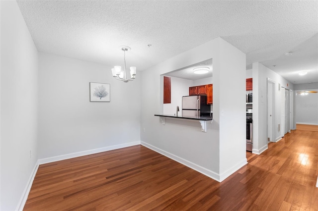 2041 Dixie Belle Dr Unit 2041C, Orlando, FL 32812 - kitchen featuring appliances with stainless steel finishes, wood finished floors, dark countertops, a breakfast bar, and a chandelier