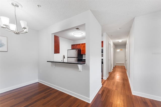 2041 Dixie Belle Dr Unit 2041C, Orlando, FL 32812 - kitchen with freestanding refrigerator, dark countertops, a breakfast bar, wood finished floors, and a chandelier