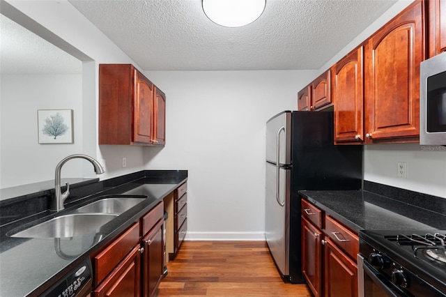 2041 Dixie Belle Dr Unit 2041C, Orlando, FL 32812 - kitchen with wood finished floors, stainless steel appliances, a textured ceiling, dark stone countertops, and dark brown cabinets