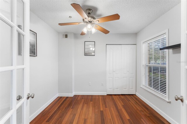 2041 Dixie Belle Dr Unit 2041C, Orlando, FL 32812 - unfurnished bedroom featuring dark wood finished floors, a textured ceiling, a closet, ceiling fan, and french doors
