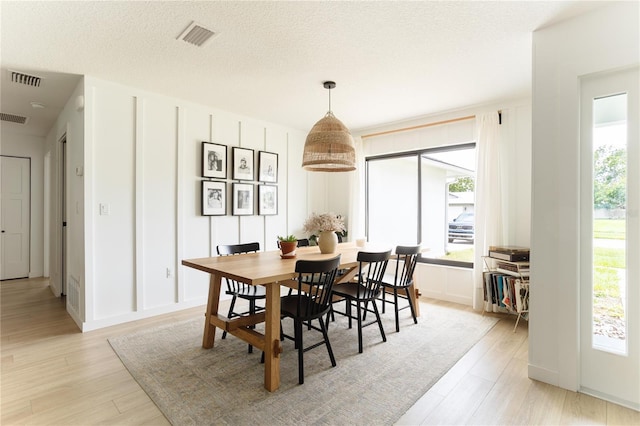 3920 Basswood Dr, Sarasota, FL 34232 - dining area with healthy amount of natural light, light wood-style flooring, a textured ceiling, and a decorative wall