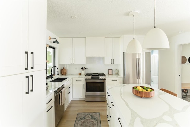 3920 Basswood Dr, Sarasota, FL 34232 - kitchen featuring appliances with stainless steel finishes, light stone countertops, a textured ceiling, decorative light fixtures, and light wood-type flooring