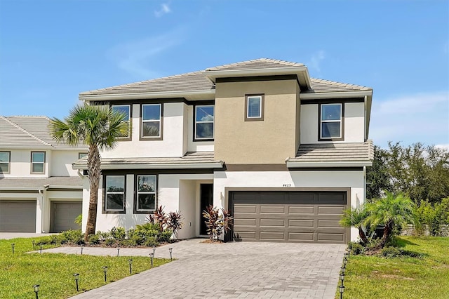 4429 Ganesha Loop, Kissimmee, FL 34746 - view of front facade featuring a garage, decorative driveway, stucco siding, and a tiled roof