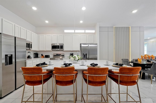 4429 Ganesha Loop, Kissimmee, FL 34746 - kitchen featuring stainless steel appliances, light countertops, white cabinets, a kitchen island, and a breakfast bar