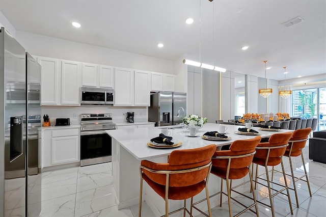 4429 Ganesha Loop, Kissimmee, FL 34746 - kitchen featuring stainless steel appliances, light countertops, hanging light fixtures, an island with sink, and a kitchen bar