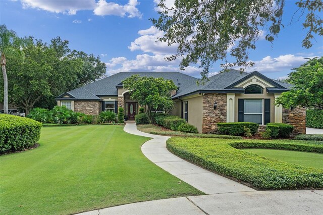 1224 Northern Way, Winter Springs, FL 32708 - view of front facade with stone siding, a front yard, stucco siding, and a shingled roof