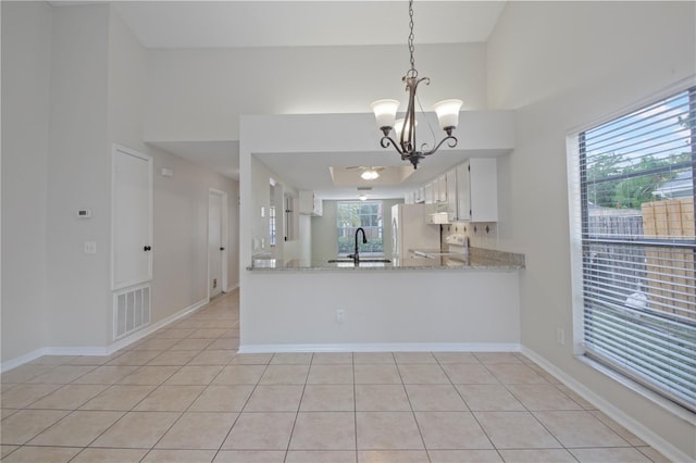 1026 Mccully Ct, Oviedo, FL 32765 - kitchen featuring a towering ceiling, freestanding refrigerator, a chandelier, light tile patterned floors, and white cabinets
