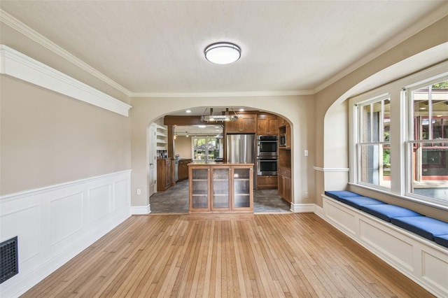 524 S Lakeview Ave, Winter Garden, FL 34787 - unfurnished living room with arched walkways, light wood-type flooring, crown molding, wainscoting, and a decorative wall