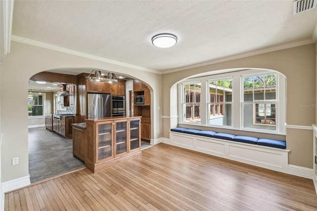 524 S Lakeview Ave, Winter Garden, FL 34787 - kitchen with arched walkways, stainless steel appliances, light wood finished floors, wall chimney exhaust hood, and ornamental molding