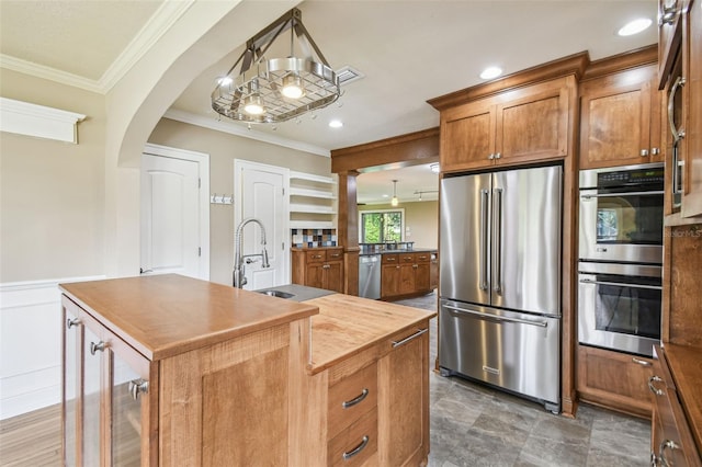 524 S Lakeview Ave, Winter Garden, FL 34787 - kitchen with appliances with stainless steel finishes, arched walkways, ornamental molding, brown cabinets, and a kitchen island with sink