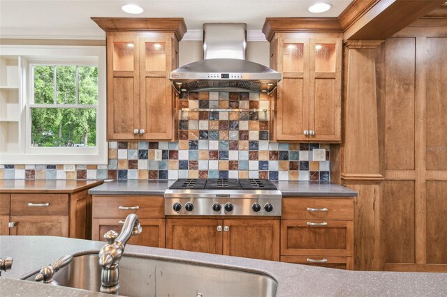524 S Lakeview Ave, Winter Garden, FL 34787 - kitchen featuring wall chimney range hood, stainless steel gas stovetop, crown molding, brown cabinetry, and decorative backsplash