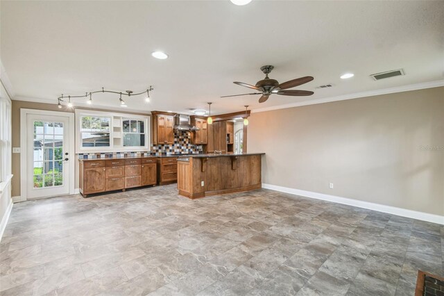 524 S Lakeview Ave, Winter Garden, FL 34787 - kitchen with brown cabinets, crown molding, wall chimney exhaust hood, a peninsula, and a kitchen bar