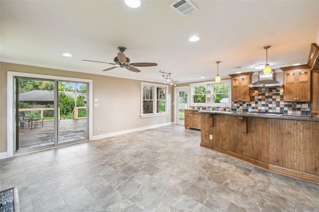524 S Lakeview Ave, Winter Garden, FL 34787 - kitchen with wall chimney exhaust hood, a ceiling fan, crown molding, brown cabinetry, and tasteful backsplash