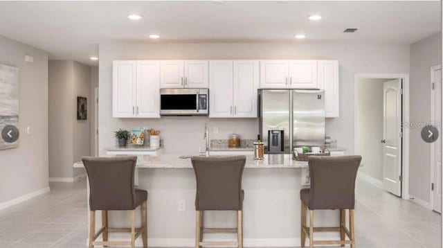 305 Cadence Gln SW, Lake City, FL 32024 - kitchen with appliances with stainless steel finishes, light tile patterned floors, white cabinets, a center island with sink, and recessed lighting