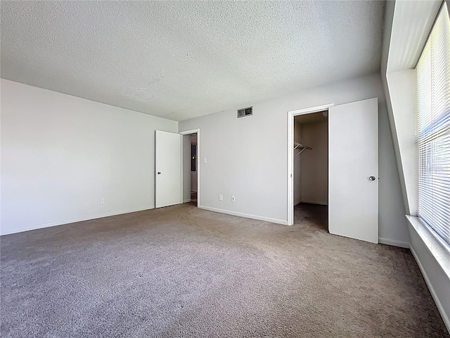 200 St Andrews Blvd Unit 911, Winter Park, FL 32792 - unfurnished bedroom with carpet flooring, multiple windows, a textured ceiling, and a walk in closet